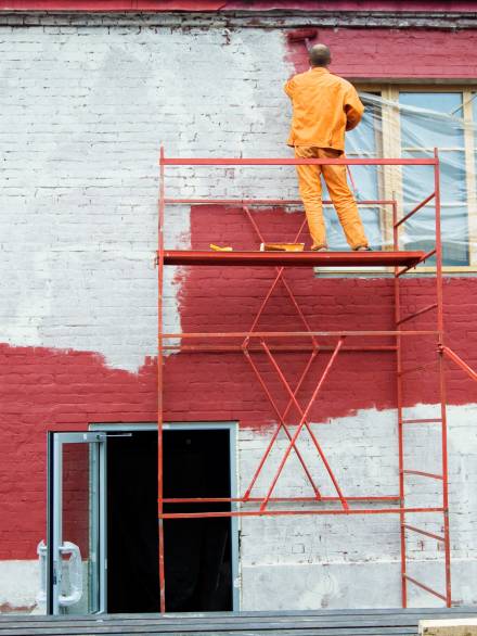 Painting in red Man painting a brick wall in red